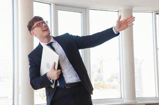 右手でパソコンを持ち手を伸ばすメガネ男性 男性,外国人,笑顔の写真素材