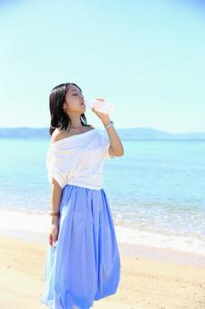 海辺で水を飲む女性 海辺で水を飲む女性 女性,海,夏の写真素材
