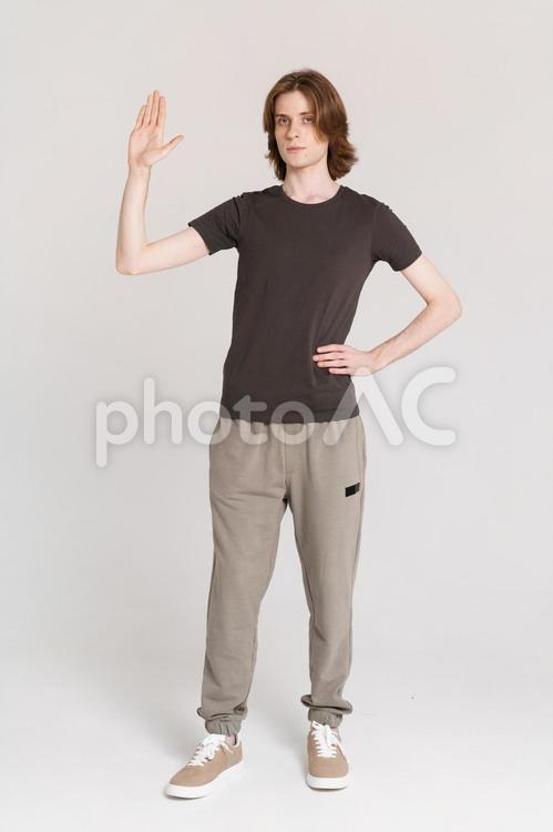 右手をあげる男性 男性,腰に手,ポーズの写真素材