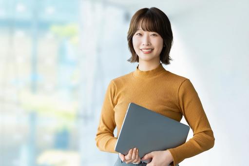 ノートパソコンを持って微笑む女性 ノートパソコンを持って微笑む女性 女性,パソコン,ビジネスの写真素材