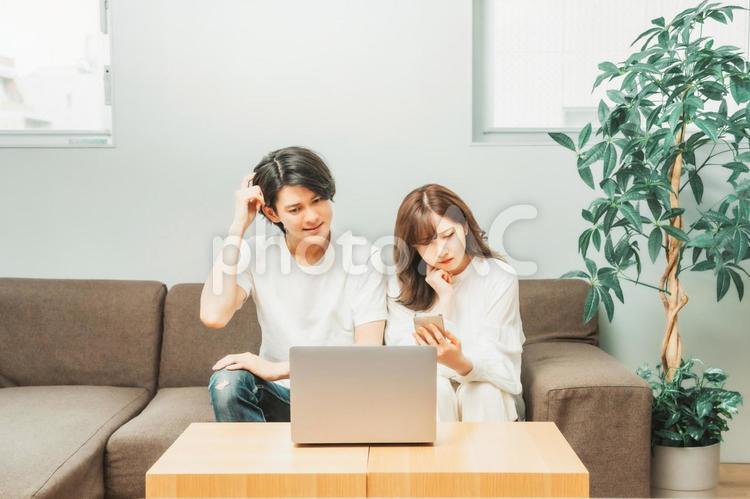 ノートパソコンとスマホを使う男女（困る） ノートパソコン,スマホ,困るの写真素材
