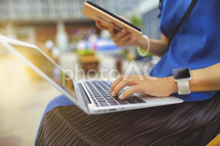 屋外でスマートフォンとラップトップを使用する女性の手元クローズアップ パソコン,ラップトップ,ノートパソコンの写真素材