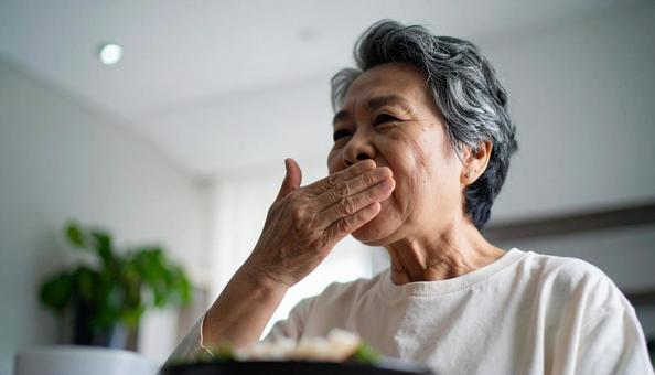 食事中、歯が痛む高齢者女性 食事中、歯が痛む高齢者女性の写真