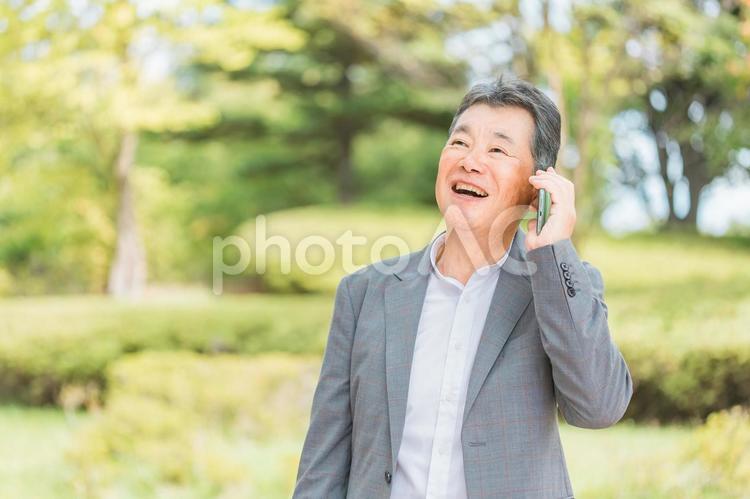 スマホで電話・通話する笑顔の高齢者男性 高齢者,スマホ,通話の写真素材