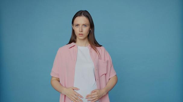 カメラ目線でお腹を触る女性 カメラ目線でお腹を触る女性の写真