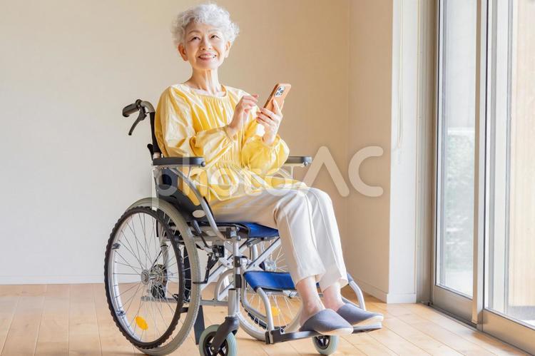 車椅子に乗ってスマホを使うシニア女性 シニア,スマートフォン,検索の写真素材