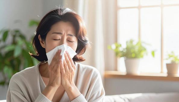ティッシュで鼻をかむ日本人のミドル女性の写真