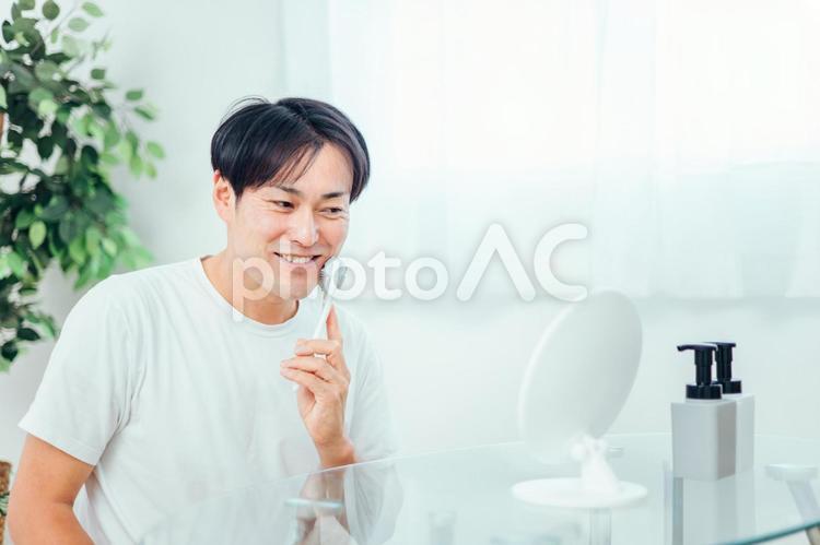 美顔ローラーを使う男性（笑顔） 美顔ローラー,顔痩せ,むくみの写真素材