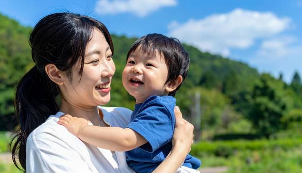 青空の下、子供を抱っこする母親 青空の下、子供を抱っこする母親の写真