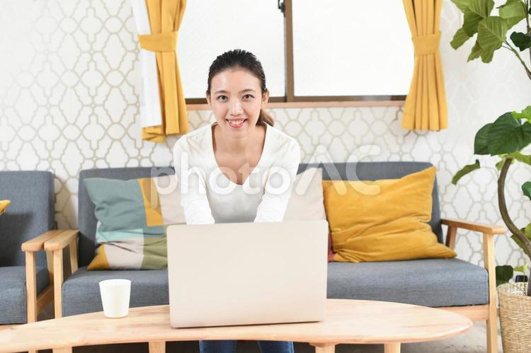 ノートパソコンと笑顔の若い女性（カメラ目線） 女性,パソコン,テレワークの写真素材