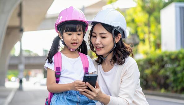防災訓練 ヘルメットをかぶった女の子と母 防災訓練 ヘルメットをかぶった女の子と母の写真