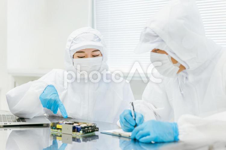 クリーンルームで精密機器を扱う女性 クリーンスーツ,打ち合わせ,ミーティングの写真素材