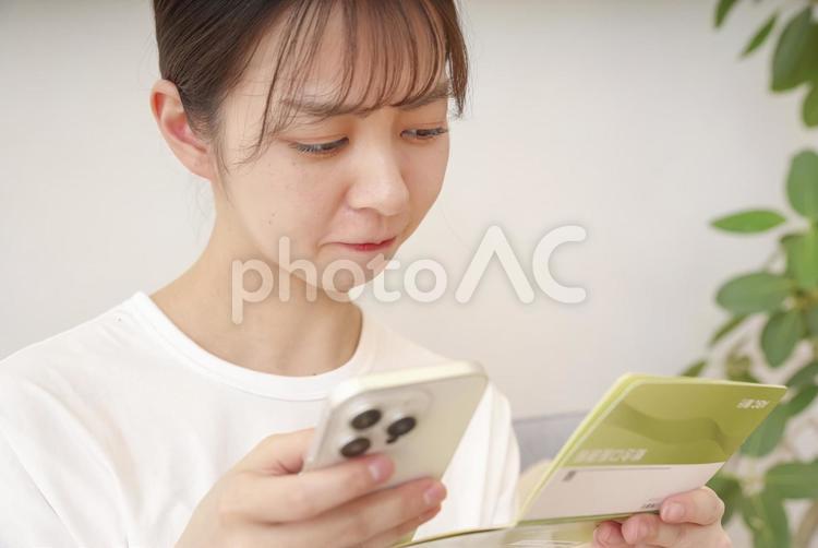 通帳を見て複雑な表情をする女性 女性,悩む,ショックの写真素材