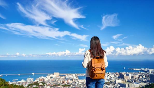 青空の下、遠くの景色を眺める女性の後ろ姿 青空の下、遠くの景色を眺める女性の後ろ姿の写真