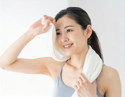 トレーニング後の汗を拭く笑顔の女性 トレーニング後の汗を拭く笑顔の女性の写真