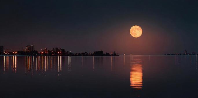 夜空に浮かぶオレンジ色の月と静かな湾 夜空に浮かぶオレンジ色の月と静かな湾の写真