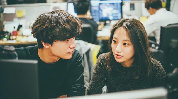 デスクで和やかに会話する男女 デスクで和やかに会話する男女の写真
