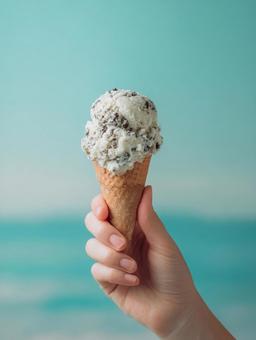 コーンに乗ったチョコミントアイスを持つ手 コーンに乗ったチョコミントアイスを持つ手の写真