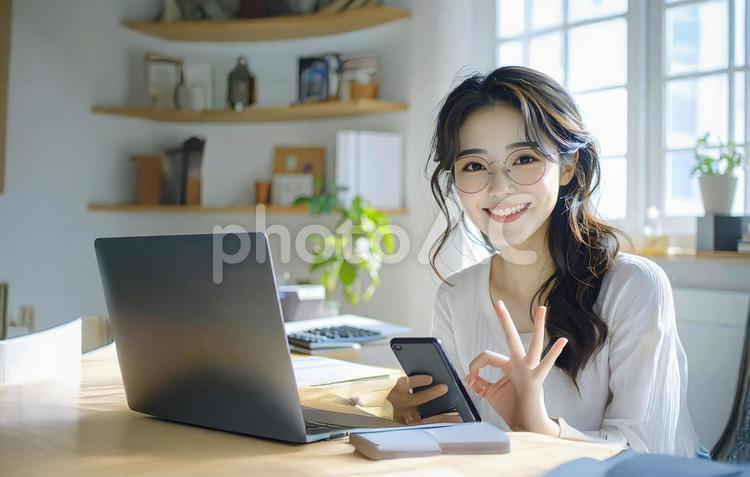 家計がうまくいきスマホ片手に微笑む女性 パソコン,家計簿,節約の写真素材