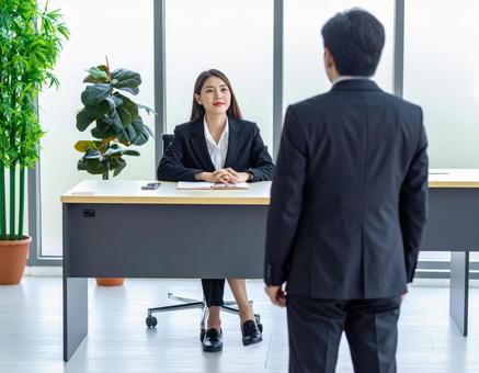 女性上司とその前に立つサラリーマンの部下の写真