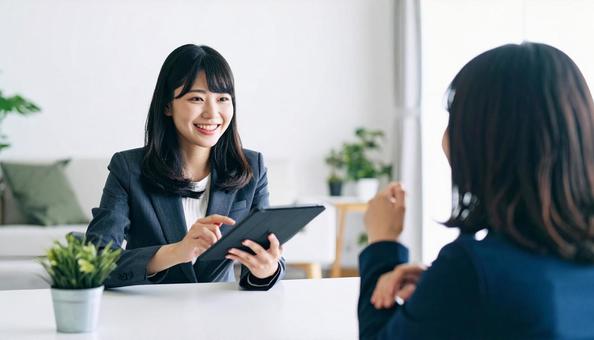 タブレットを使って説明する女性営業マン タブレットを使って説明する女性営業マンの写真