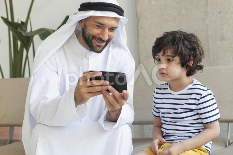 父の持つスマホを見ている男の子 親子,父子,外国人の写真素材