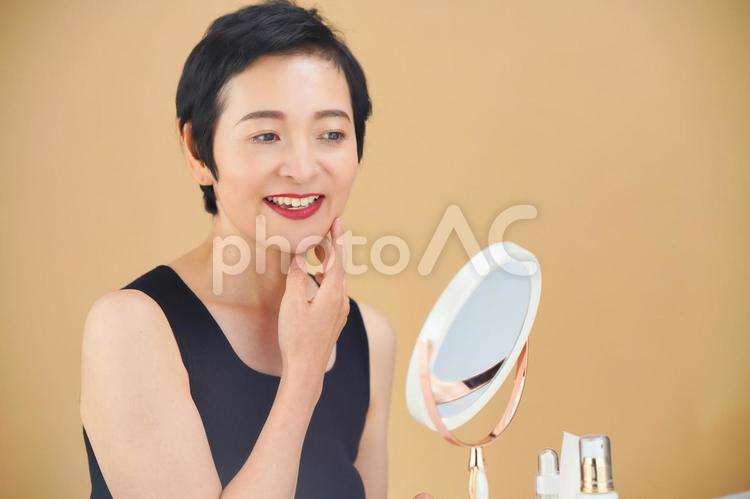 スキンケアをするショートカットの女性（ベージュ背景） 女性,日本人,50代の写真素材