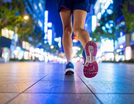 夏の夜のネオン街をランニングする女性 夏の夜のネオン街をランニングする女性の写真