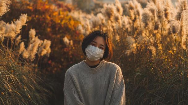 秋風に揺れるススキとマスク姿の女性 秋風に揺れるススキとマスク姿の女性の写真