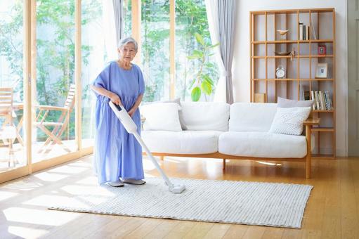 ラグの上に立ち掃除機を持つ高齢女性 女性,掃除,掃除機の写真素材