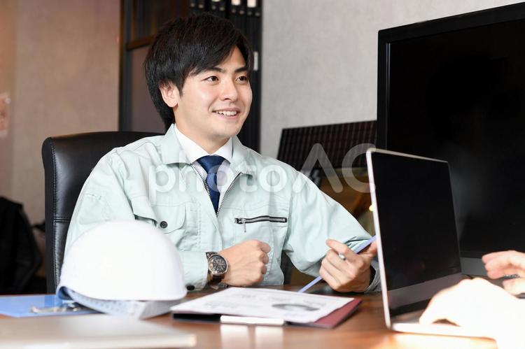 取引先と会議中の若いアジア人の男性作業員 作業員,男性,作業服の写真素材