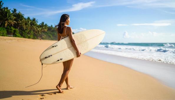 サーフボードを持って砂浜を歩く日本人女性 サーフボードを持って砂浜を歩く日本人女性の写真