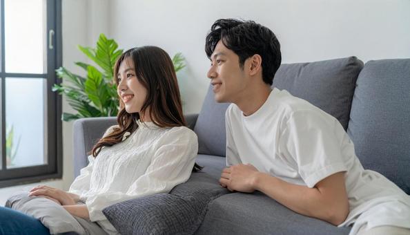 リビングでくつろぐ若いカップルの横顔の写真