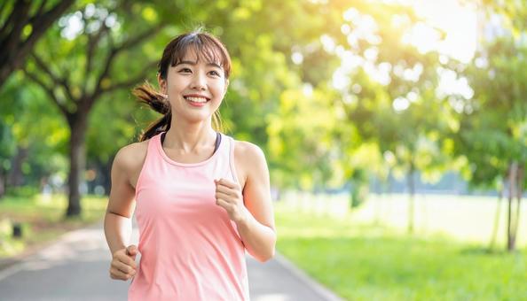 笑顔でジョギングする若い女性 笑顔でジョギングする若い女性の写真