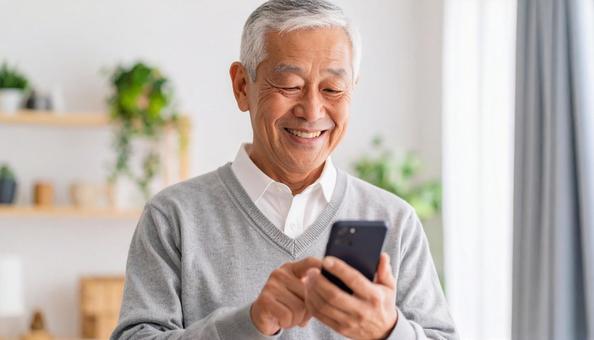 スマホを操作して笑顔の高齢の日本人男性 スマホを操作して笑顔の高齢の日本人男性の写真