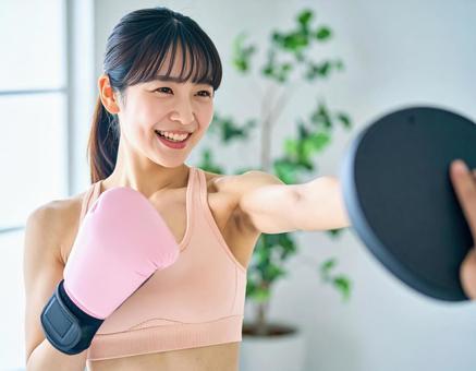 ジムでボクササイズをする若い女性 ジムでボクササイズをする若い女性の写真