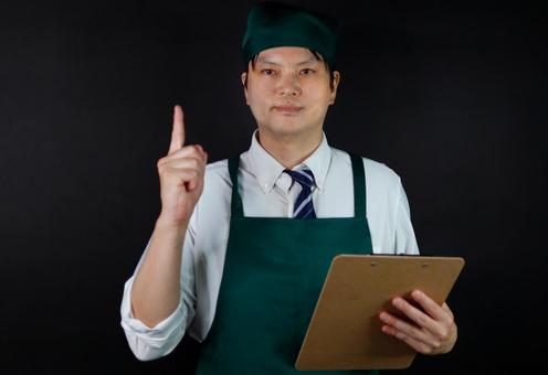 エプロンの男性店員指差す エプロンの男性店員指差すの写真