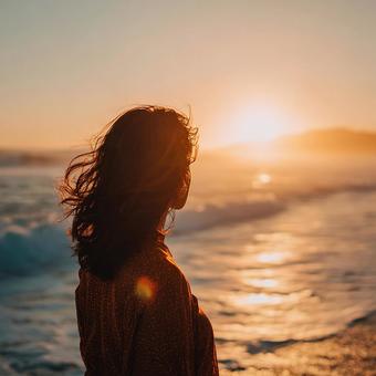 ビーチで夕日を眺める女性の後ろ姿 ビーチで夕日を眺める女性の後ろ姿の写真