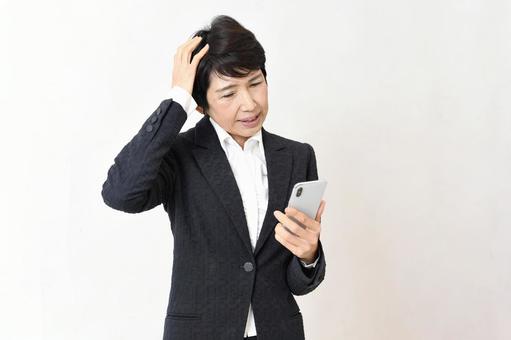 スマホ操作に困っているアジア人の中年女性 中年女性,中高年,シニア女性の写真素材