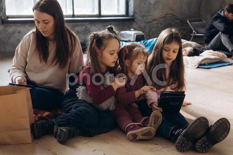 タブレットを見る女性と女の子と遠くに男性と寝転ぶ女性 女性,女の子,人物の写真素材