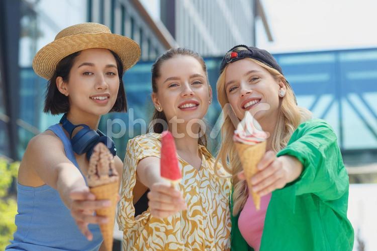 ソフトクリームとキャンディーを前に出してカメラ目線の女性 女性,友達,仲間の写真素材