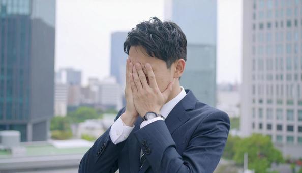 オフィスビルの屋上で苦悩するビジネスマン オフィスビルの屋上で苦悩するビジネスマンの写真