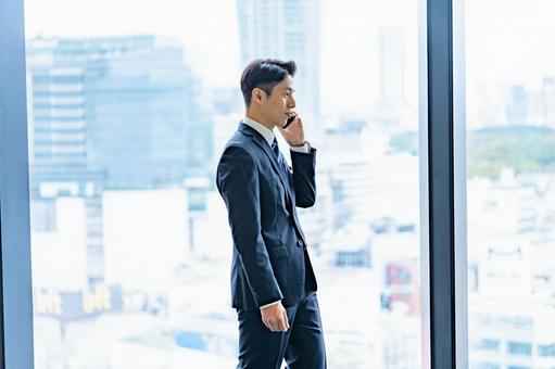 高層ビルで電話をするビジネスマン 高層ビルで電話をするビジネスマン ビジネスマン,男性,スーツの写真素材