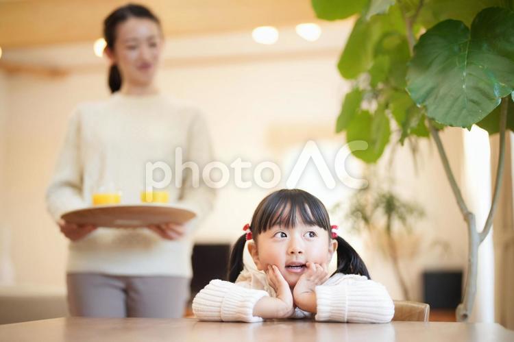 両手で頬を触る娘とジュースを運ぶ母 女性,母,女の子の写真素材