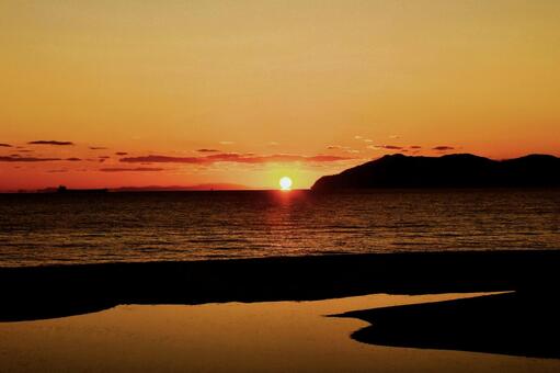 水平線のダルマ夕日と海と川の境界線 ダルマ夕日,虹ヶ浜海水浴場,山口県光市の写真素材