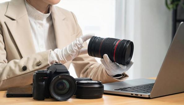 カメラのレンズを査定する女性 カメラのレンズを査定する女性の写真