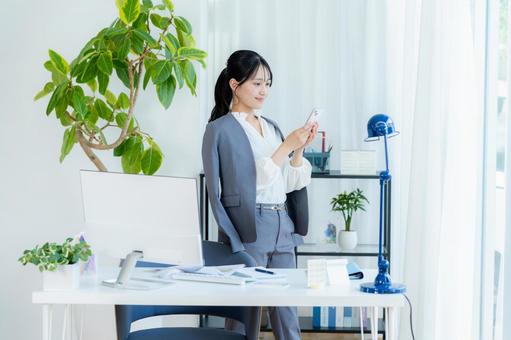 オフィスでスマホを使うビジネスウーマン ビジネスウーマン,スマホ,笑顔の写真素材