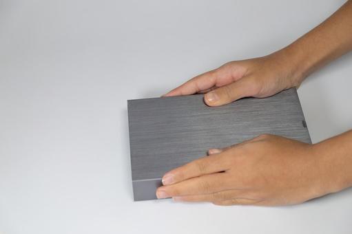 白い背景の上で灰色に加工された板を持つ手 板,手,灰色の写真素材