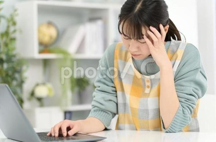 パソコンで頭を抱えるエプロンを着た女性 女性,ノートパソコン,頭痛の写真素材