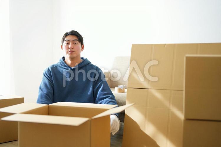 段ボール箱に囲まれる引っ越しの荷造り中の男性 引っ越し,一人暮らし,男性の写真素材